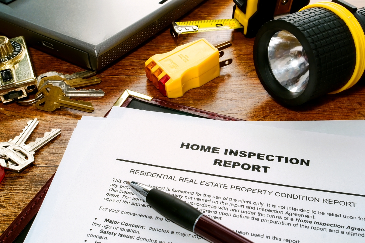 Home inspection report document on a desk with keys, flashlight, and tools, emphasizing preparation for home inspections.